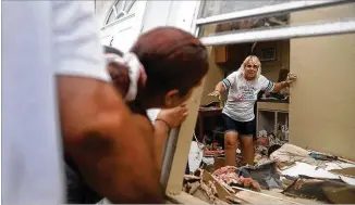  ?? JOE RAEDLE / GETTY IMAGES ?? After Hurricane Harvey hit, Donna Raney makes her way out of the wreckage of her tilted apartment home in Rockport, Texas, on Saturday as Daisy Graham offers to help her out the window.