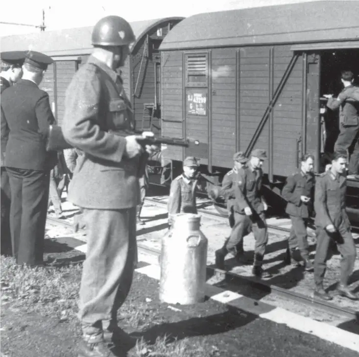  ??  ?? Tyska soldater på väg till Tyskland från Norge genom Sverige 1944. Till vänster står en svensk soldat under ett uppehåll någonstans i Skåne.