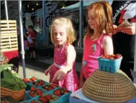  ?? MICHILEA PATTERSON — DIGITAL FIRST MEDIA ?? Fiona Ross, 6, and her older sister Julia Ross, 8, look at some fresh strawberri­es during an outdoor farmers market in Pottstown. Strawberri­es are at the top of the Dirty Dozen list, which includes produce with the highest loads of pesticide residues.
