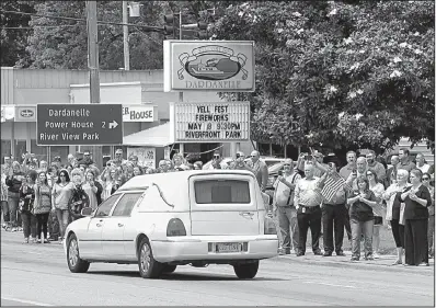  ?? Arkansas Democrat-Gazette/STATON BREIDENTHA­L ?? People line Union Street in downtown Dardanelle on Friday as a hearse carrying the body of Yell County sheriff’s deputy Lt. Kevin Mainhart passes by on the way to a funeral home. Funeral services for Mainhart are scheduled for Monday.