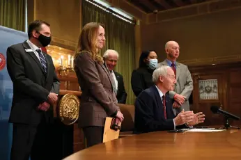  ?? (Arkansas Democrat-Gazette/Stephen Swofford) ?? Governor Hutchinson, surrounded by legislator­s and educators from Arkansas, signs teacher salary bills SB504 and HB1614 during a press conference at the Arkansas State Capitol on Monday, April 12. The bills will increase the target median salary for teachers to $52,822, an increase of $2,000, Hutchinson said.