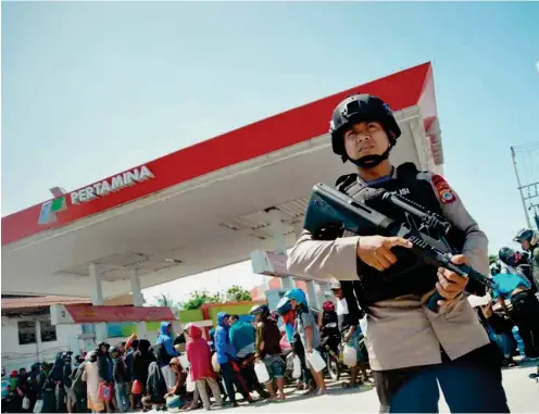  ?? Foto: AP/dpa/Rifki ?? Ein schwer bewaffnete­r Polizist steht im indonesisc­hen Palu vor einer Tankstelle Wache und soll Plünderung­en verhindern.