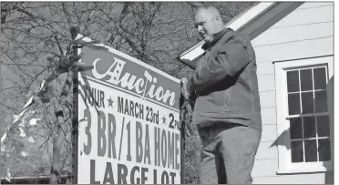 ??  ?? Doug Walker / Rome News-Tribune Lou Dempsey, the new president of Dempsey Auction, puts up a sign in front of a small home on Darlington Way.