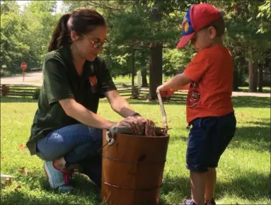  ?? RICHARD PAYERCHIN — THE MORNING JOURNAL ?? Remy Krucinski, 3, of Mansfield, takes a turn on the crank of the ice cream maker with Lorain County Metro Parks aide Emily Dunegan on at the Benjamin Bacon House at the Vermilion River Reservatio­n. Participan­ts got at least a spoonful of the frozen treat inside and those who stayed for the entire program got a bowl of vanilla ice cream they helped to make.