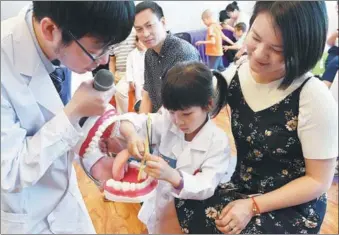  ?? LIU KEGENG / CHINA NEWS SERVICE ?? A mom and her daughter learn how to brush teeth properly at a charity event in Fuzhou city, Fujian province on Mother’s Day on May 14.