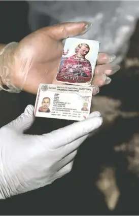  ?? NEW YORK TIMES PHOTO BY VICTOR J. BLUE ?? A volunteer with Águilas del Desierto — Eagles of the Desert — holds a prayer card and a Mexican ID card bearing the name of Adrián Luna found next to a body in the McCain Valley of southern California on July 7.