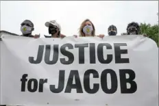  ?? Morry Gash/ Associated Press ?? Participan­ts in a community gathering at the site of Jacob Blake’s shooting hold a sign Tuesday during speeches in Kenosha, Wis.