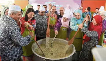  ??  ?? All together now: Dr Wan Azizah (third from right) with (second from left) Yeoh and the ministry’s secretary-general Datuk Dr Rose Lena Lazemi (second from right) stirring the bubur lambuk with the centre’s residents during the visit to Darul Hanan care centre in Pongsu Seribu. — Bernama