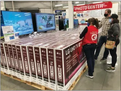  ?? (AP/David Zalubowski) ?? A Costco employee helps customers on Nov. 18, as they consider buying a big-screen television in Sheridan, Colo. U.S. consumer confidence fell in November as rising coronaviru­s cases pushed Americans’ confidence to the lowest level since August.