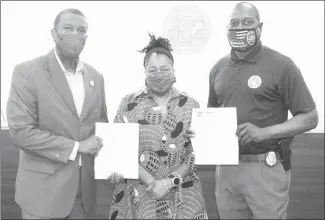  ?? Katie West • Times-Herald ?? Vanessa Brayboy, center, presents Forrest City Mayor Cedric Williams, left, and Forrest City Police Chief Deon Lee with award letters for grants she wrote for funding to serve domestic violence victims. The grants will help provide items such as clothing, grooming supplies, sanitation supplies and shelter to victims of domestic violence.