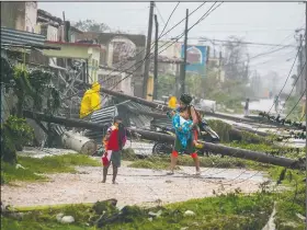  ?? AP/DESMOND BOYLAN ?? Residents walk near downed power lines felled by Hurricane Irma on Saturday in Caibarien, Cuba.