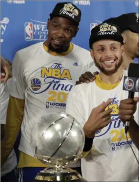  ?? ERIC GAY — THE ASSOCIATED PRESS ?? The Golden State Warriors’ Kevin Durant, left, and Stephen Curry, right, stand on stage by the trophy after beating the San Antonio Spurs 129-115in Game 4of the NBA basketball Western Conference finals, Monday in San Antonio.