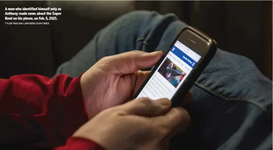  ?? TYLER PASCIAK LARIVIERE/SUN-TIMES ?? A man who identified himself only as Anthony reads news about the Super Bowl on his phone, on Feb. 5, 2021.