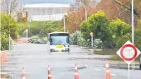  ??  ?? A school bus negotiates a section of flooded road in Tauranga.