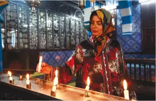  ?? (Anis Mili/Reuters) ?? A JEWISH WOMAN places a candle during the first day of pilgrimage at the Ghriba synagogue in Djerba.