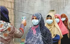  ?? Reuters ?? Vaccinator­s wear protective masks as they get their temperatur­e checked during an anti-polio campaign in Karachi.
