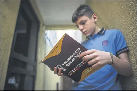 ?? Foto: EFE ?? Un joven aficionado argentino ojea el albúm de cromos oficial de Panini para el Mundial de Qatar 2022