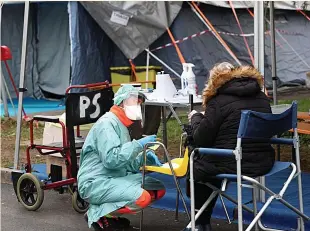  ??  ?? A health worker tends to a woman at a tented facility in a Brescia hospital in Italy