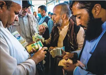  ?? Marcus Yam Los Angeles Times ?? TRADERS ENGAGE in negotiatio­ns at the Sarai Shahzadah currency exchange market in Kabul, Afghanista­n, which opened Sept. 4 for the first time since the Taliban regained control of the country last month.