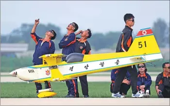  ?? WONG MAYE-E / ASSOCIATED PRESS ?? DPRK aviation staff members watch a remote-controlled plane demonstrat­ion at Kalma Airport in the port city of Wonsan, DPRK, on Sunday.