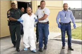  ?? KIMBERLY C. MOORE/THE LEDGER VIA ASSOCIATED PRESS ?? Quadruple murder suspect Bryan Riley is led from the Polk County Sheriff’s Office in Lakeland, Florida, on Sept. 5 by Deputy Steve Neil (left), Captain Bart Davis (center) and Detective Brett Bulman.