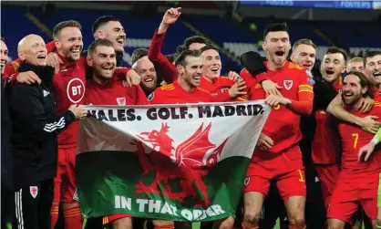  ??  ?? Gareth Bale celebrates after Wales qualified for Euro 2020, with a flag saying: “Wales. Golf. Madrid. In that order”. Photograph: Athena Pictures/Getty Images