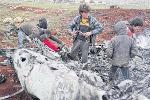  ??  ?? SURVEYING THE DAMAGE: Syrians inspect the wreckage of a military helicopter belonging to government forces after it was shot down in Aleppo province on Friday.