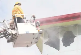  ?? (Photo by Keno George) ?? Firefighte­rs sprayed water into the burning building through some of the broken windows.