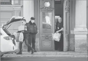  ?? AP PHOTO ?? Men carry boxes and packs out from the U.S. consulate as a Russian police officer guards the entrance in St. Petersburg, Russia.