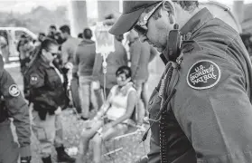  ?? John Moore / Getty Images ?? A Border Patrol agent holds an IV bag last month for a migrant suffering from heat exhaustion after taking her into custody.