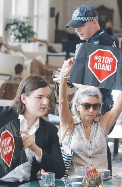  ??  ?? SIGNS: Protesters are spoken to by police at Pullman Cairns Internatio­nal hotel before