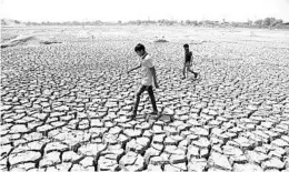  ?? AJIT SOLANKI/AP 2016 ?? Boys walk through a dried patch of Chandola Lake in Ahmedabad, India. The 2010s averaged 58.4 degrees worldwide, or 1.4 degrees higher than the 20th century average.