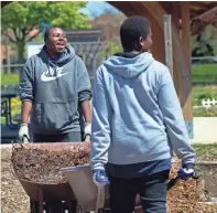  ?? ANGELA PETERSON / MILWAUKEE JOURNAL SENTINEL ?? Students Kewon Holmes (left) and Brandon Gilmore, both 17, haul mulch at Alice’s Garden, 2136 N. 21st St., on Monday. For more photos, go to jsonline.com/news.