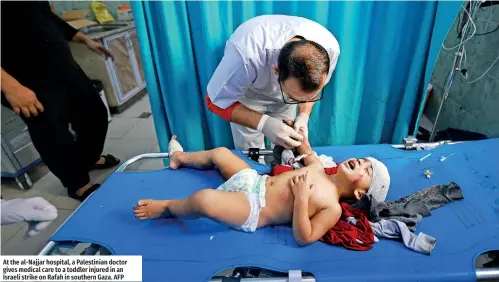  ?? ?? At the al-Najjar hospital, a Palestinia­n doctor gives medical care to a toddler injured in an Israeli strike on Rafah in southern Gaza. AFP