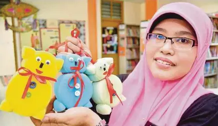  ??  ?? Puan Maizura Abdul Isa menunjukka­n beruang teddy hiasan yang dihasilkan daripada span terpakai.