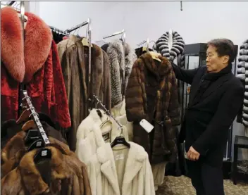  ??  ?? In this photo taken March 16, Benjamin Lin holds up a fur coat at the B.B. Hawk showroom in San Francisco. San Francisco could become the largest U.S. city to ban the sale of fur items, a move that would hearten animal lovers but frustrate niche...