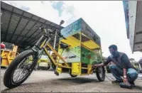  ?? ANDI M. RIDWAN / SIPA USA ?? A city employee charges an electric tricycle that serves to remove waste in Bogor, West Java, Indonesia, in August. The tricycle provides an environmen­tally friendly answer to keeping the city clean.