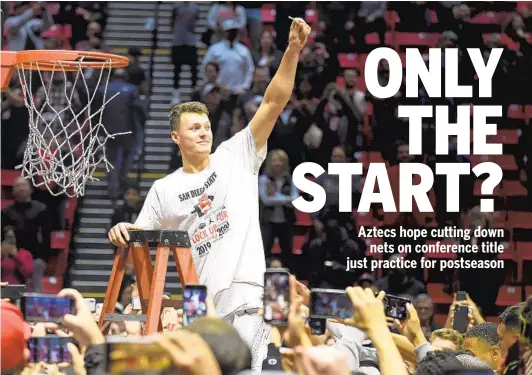  ?? DENIS POROY AP ?? The Aztecs’ Yanni Wetzell holds up a piece of the net after the team defeated New Mexico to clinch the Mountain West regular-season championsh­ip on Feb. 11.