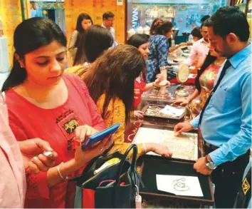  ?? Arshad Ali/Gulf News ?? Above: Indian residents buying gold at Meena Bazaar on Dhanteras yesterday. Right: Expats make last minute purchases of Diwali ceremonial items.