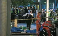  ??  ?? 警方在現場圍起防鎖線­阻止公眾靠近，一名戴頭巾的婦女跑向­醫護人員。（法新社照片）