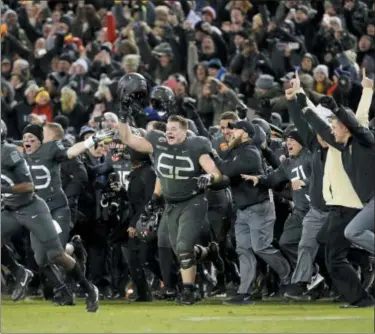  ?? PATRICK SEMANSKY — THE ASSOCIATED PRESS FILE ?? In this file photo, Army players and coaches run onto the field after defeating Navy 21-17 in an NCAA college football game in Baltimore, Md. With Army ranked No. 22, the Cadets (9-2) try to beat Navy (3-9) for the third straight time Saturday in the storied series.