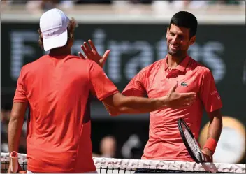  ?? EMMANUEL DUNAND/AFP VIA GETTY IMAGES ?? Novak Djokovic, right, greets Aleksandar Kovacevic after Djokovic won Monday's French Open first-round match in Paris.