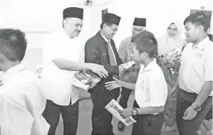  ??  ?? ARIFIN menyampaik­an buku panduan peperiksaa­n UPSR kepada calon-calon UPSR Membakut.