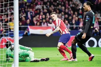  ?? — AFP photo ?? Atletico Madrid’s midfielder Saul Niguez (centre) scores the opening goal during the UEFA Champions League, round of 16, first leg match against Liverpool FC at the Wanda Metropolit­ano stadium in Madrid.
