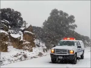  ?? The Associated Press ?? BRIEF RESPITE: This photo tweeted by the Santa Barbara County Fire Department shows a Santa Barbara Fire Department truck along E. Camino Cielo as snow falls at the 3,500 foot level on the fire footprint Thursday in Santa Barbara, Calif. Wintry weather temporaril­y loosened its grip across much of the U.S. just in time for Thanksgivi­ng, after tangling holiday travelers in wind, ice and snow and before more major storms descend today.
