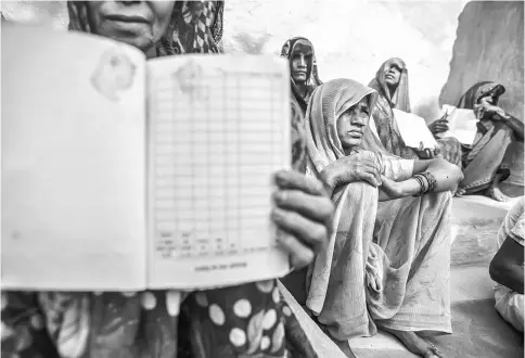  ??  ?? A woman sits listening as other villagers hold up their job cards for the rural jobs programme, known as the Mahatma Gandhi National Rural Employment Guarantee Act (MNREGA), which mandates 100 days of wages per year to rural households, during a public...