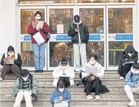  ?? AFP ?? Students are seen reading books as they arrive for the National Postgradua­te Entrance Exam in Nanjing, in China’s eastern Jiangsu province.