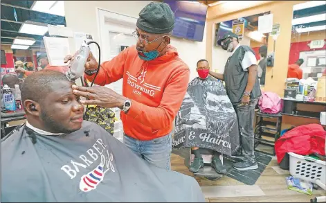  ?? (AP/Julio Cortez) ?? Kevin Fitzhugh (center left) gives Mabreco Wright (left) a haircut, as Wallace Wilson (right) cuts James McRae’s hair in Hyattsvill­e, Md. Barbers such as Fitzhugh and Wilson are members of the Health Advocates In Reach & Research program, which helps barbers and hair stylists get certified to talk to community members about health. During the pandemic, a team of certified barbers have been providing factual informatio­n to customers about vaccines, a topic that historical­ly has not been trusted by members of black communitie­s because of the health abuse the race has endured over the years.