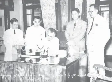  ?? Photo taken from the preserved image of the Hernaez family in Bacolod City. ?? PRESIDENT Manuel Luis Quezon signs Commonweal­th Act 326, the law converting the municipali­ty of Bacolod to a full-fledged city on June 18, 1938, in the presence of then Assemblyma­n Pedro Hernaez (2nd from right) and other government officials.