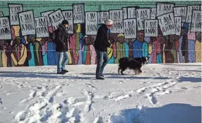  ?? ?? Jan. 16, 2018: Anthony Dinolfo and Teri Stoerger, along with her dog, Oskie, walk in the snow as they pass Marcellous Lovelace's "I Am A Man" mural on South Main Street. "I just love this weather," Stoerger said. "It's nice and cold and there's beautiful snow, you can play in it — it's great.”